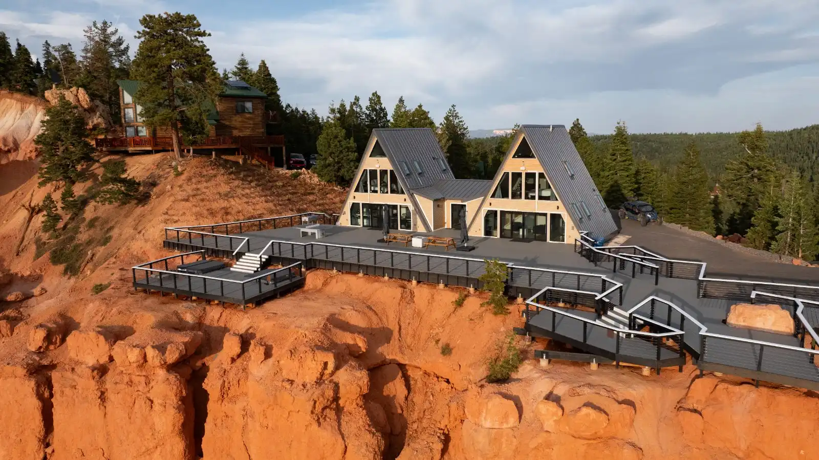 Two connected A-frame houses with a large terrace at the edge of a cliff