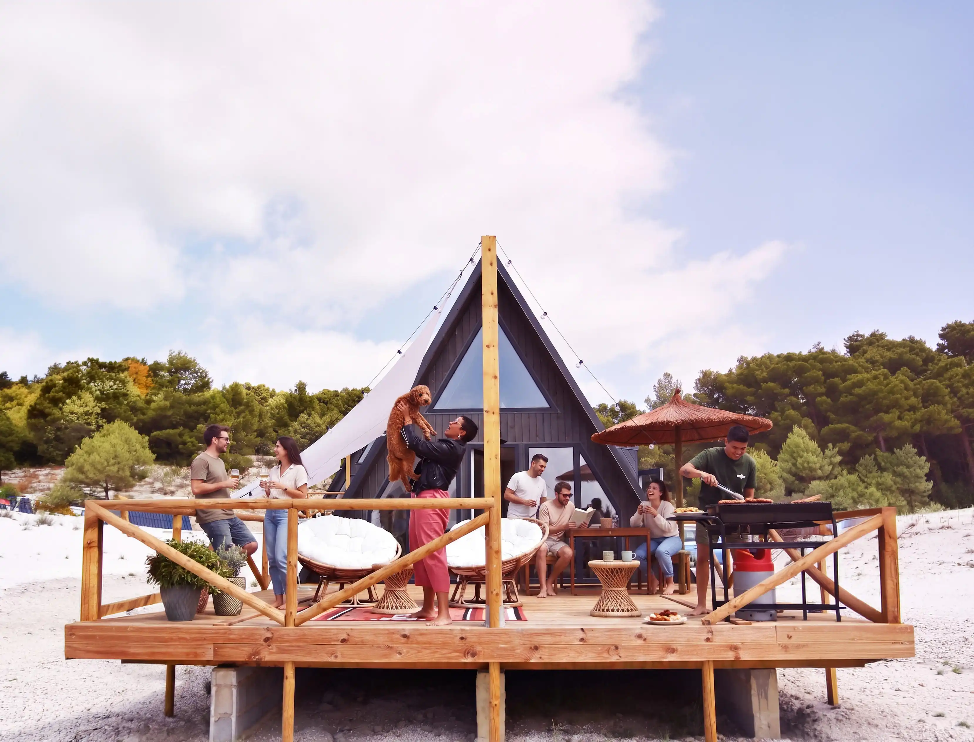 Friends enjoying a deck party and barbecue outside a modern A-frame vacation rental